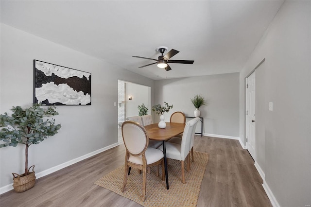 dining space featuring a ceiling fan, baseboards, and wood finished floors