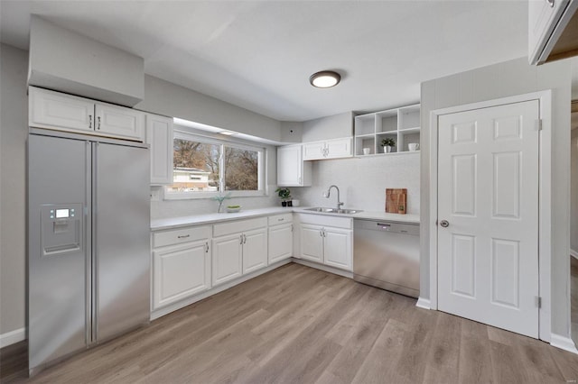 kitchen with white cabinets, built in refrigerator, light countertops, stainless steel dishwasher, and a sink