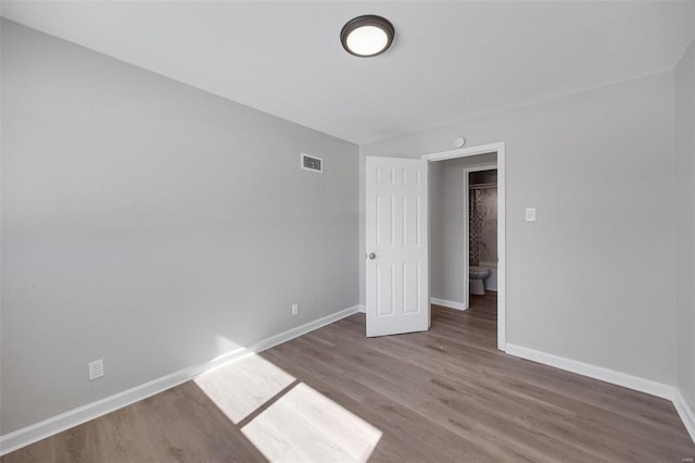 unfurnished room with visible vents, baseboards, and wood finished floors