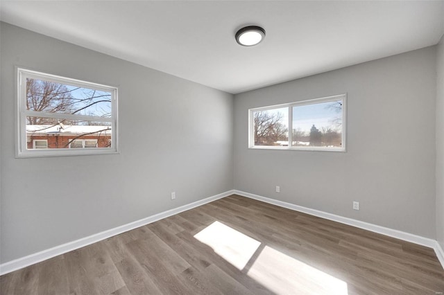 spare room with baseboards and wood finished floors