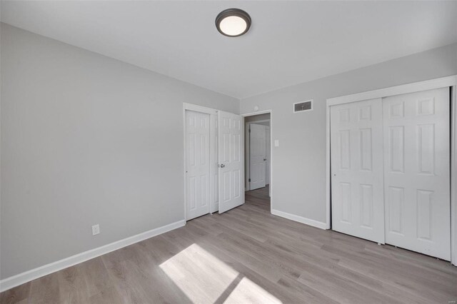 unfurnished bedroom featuring light wood-style floors, baseboards, and visible vents