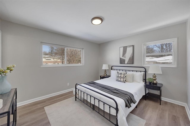 bedroom with multiple windows, baseboards, and wood finished floors