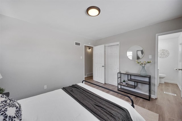 bedroom with baseboards, a closet, visible vents, and wood finished floors