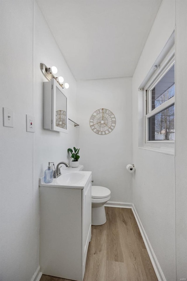 bathroom with toilet, baseboards, wood finished floors, and vanity