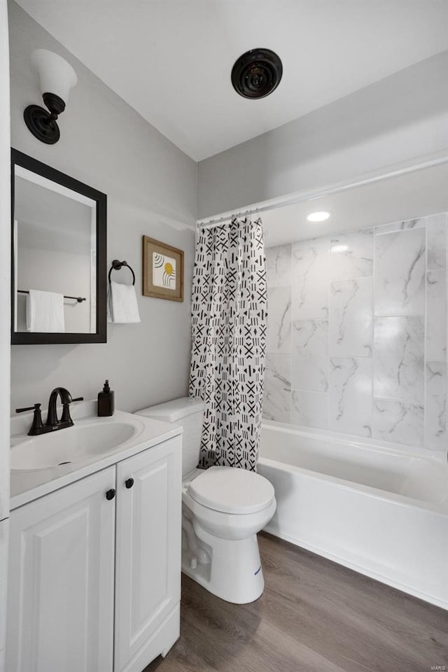 full bath with toilet, shower / tub combo, wood finished floors, and vanity