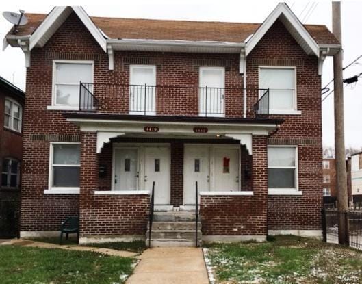 view of front of property featuring brick siding and a balcony