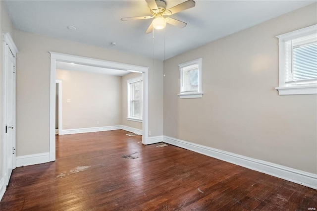 empty room with a wealth of natural light, baseboards, and dark wood-type flooring