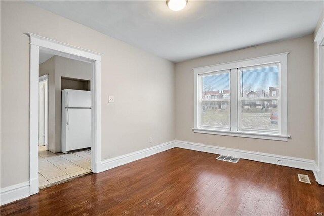 empty room with light wood-type flooring, baseboards, and visible vents