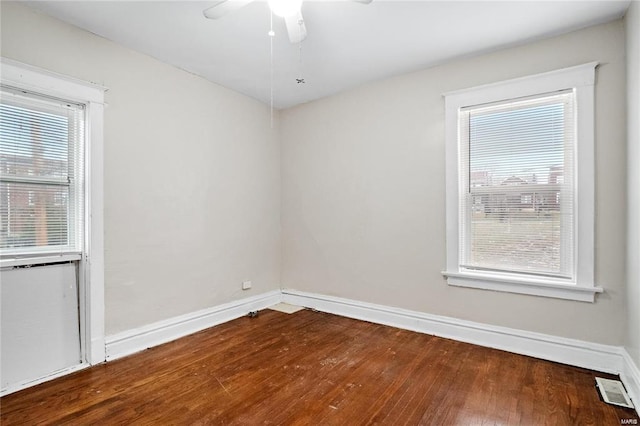 spare room featuring a ceiling fan, visible vents, baseboards, and wood finished floors