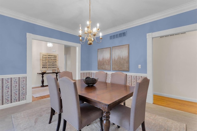 dining room with an inviting chandelier, ornamental molding, and light wood-type flooring