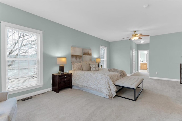 carpeted bedroom with ceiling fan, connected bathroom, and multiple windows