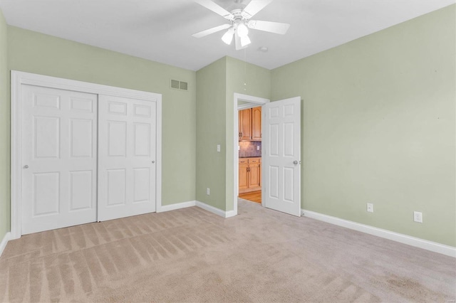 unfurnished bedroom with light colored carpet, a closet, and ceiling fan