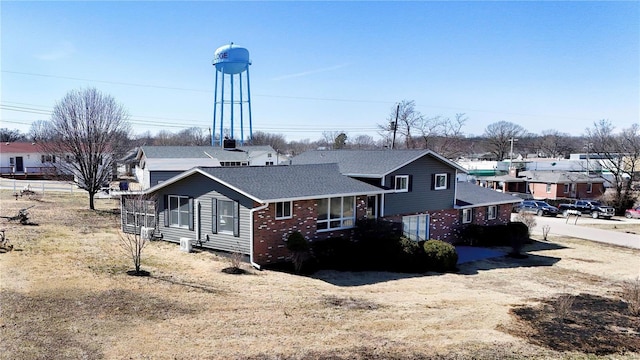 rear view of house featuring brick siding and roof with shingles