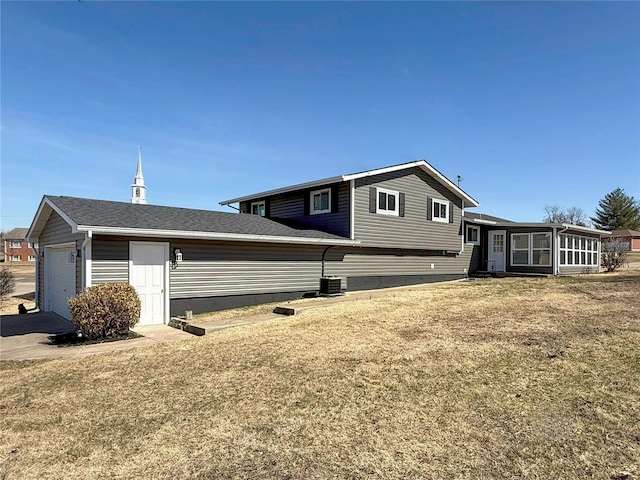 view of side of home featuring central air condition unit, a yard, roof with shingles, a sunroom, and a garage