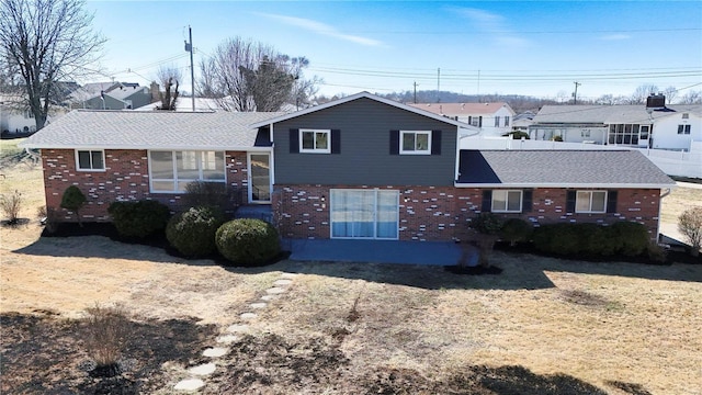 split level home with brick siding and roof with shingles