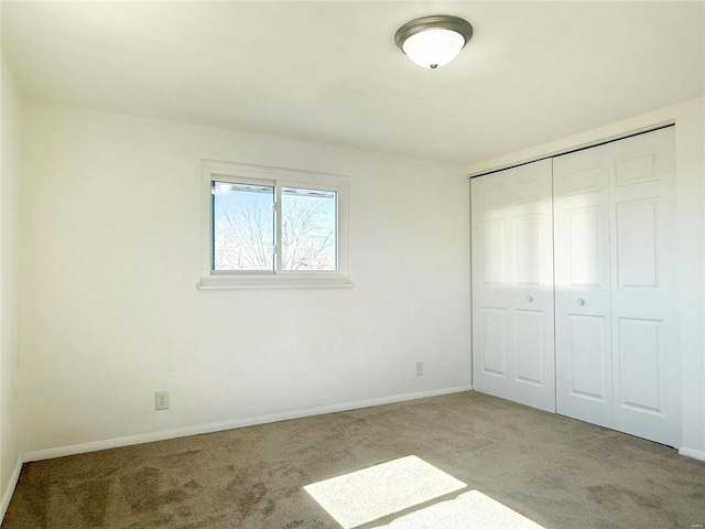 unfurnished bedroom featuring carpet, baseboards, and a closet