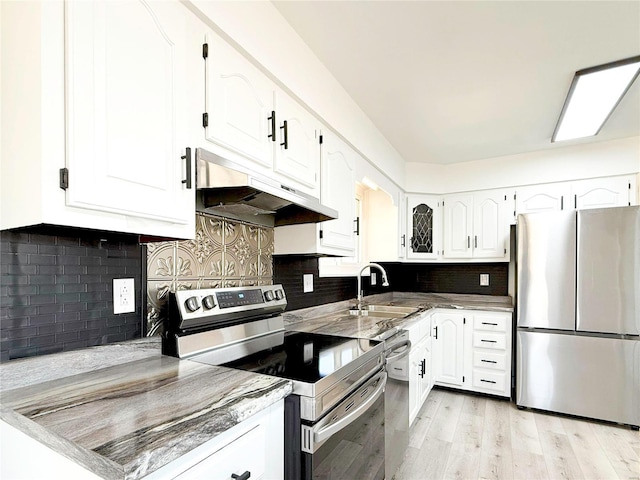 kitchen featuring light wood finished floors, under cabinet range hood, appliances with stainless steel finishes, white cabinets, and a sink