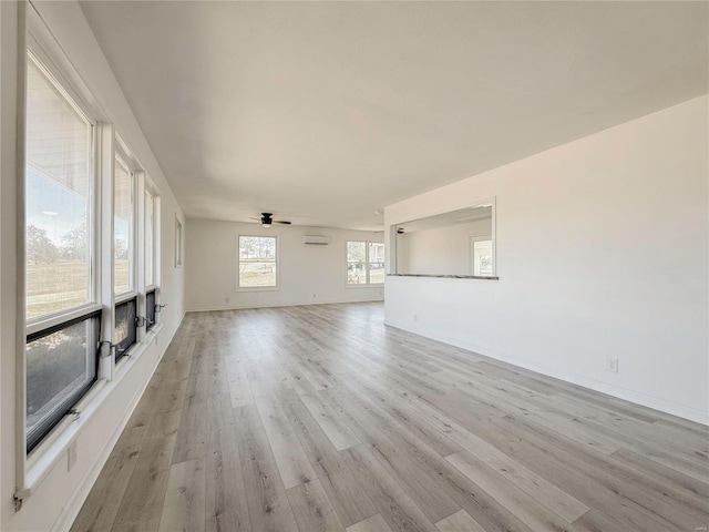 unfurnished living room with a ceiling fan, light wood-type flooring, and baseboards