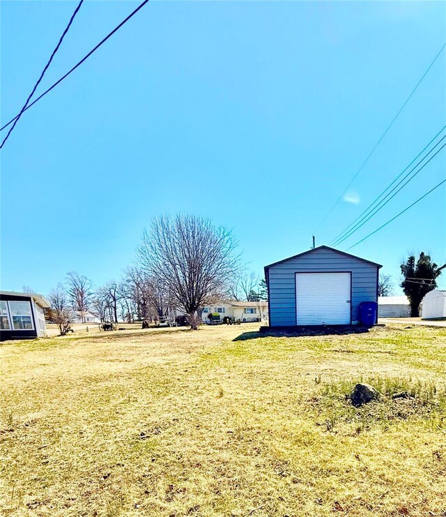 view of yard with a detached garage and an outbuilding