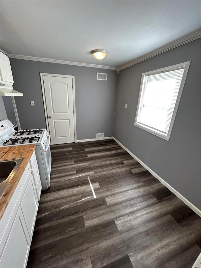 kitchen featuring butcher block counters, white cabinets, crown molding, and white gas stove