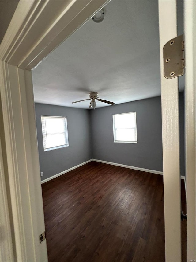 unfurnished room featuring ceiling fan, dark hardwood / wood-style floors, and a wealth of natural light