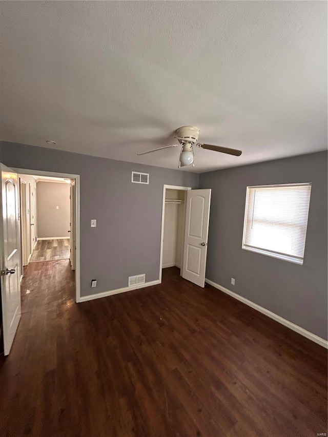 unfurnished bedroom featuring ceiling fan, dark hardwood / wood-style flooring, a closet, and a textured ceiling