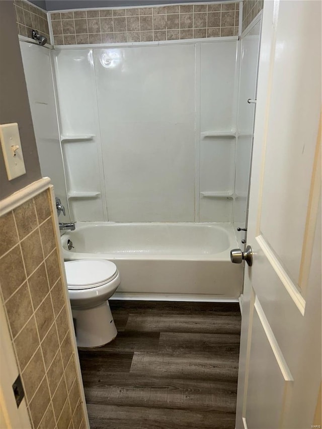 bathroom featuring hardwood / wood-style flooring, shower / washtub combination, and toilet