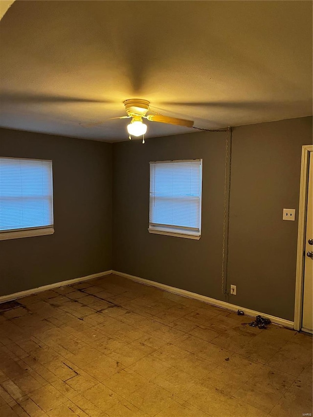 spare room featuring ceiling fan, a textured ceiling, and baseboards