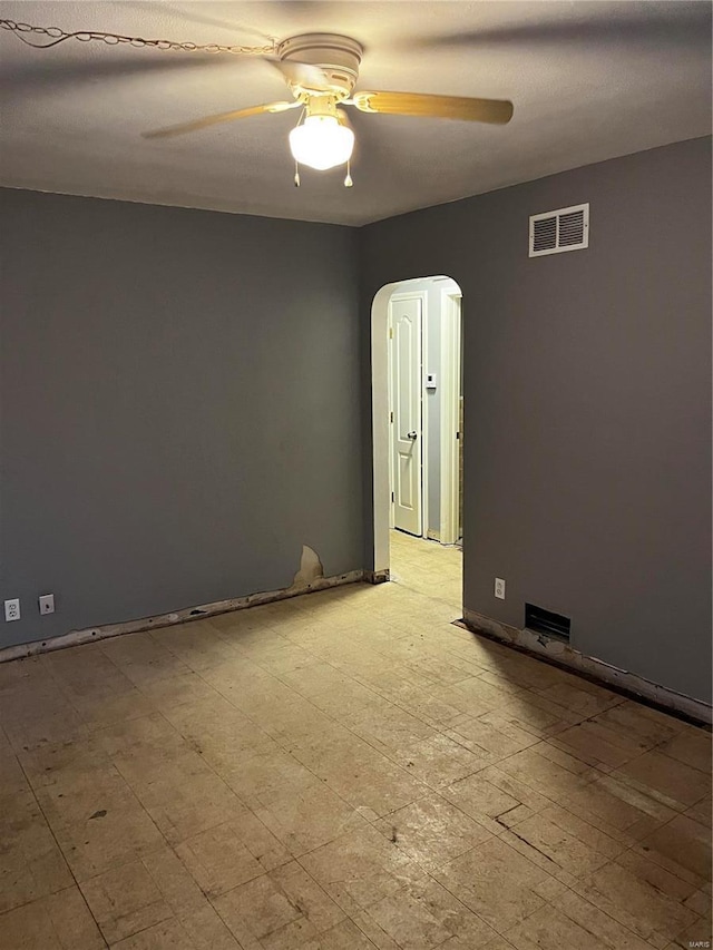 unfurnished room featuring arched walkways, visible vents, ceiling fan, and light floors