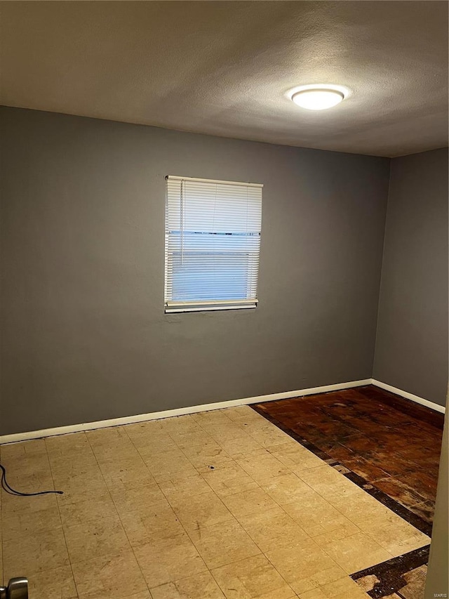 unfurnished room with baseboards, a textured ceiling, and tile patterned floors