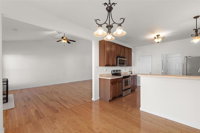 kitchen featuring light wood finished floors, ceiling fan, appliances with stainless steel finishes, hanging light fixtures, and light countertops