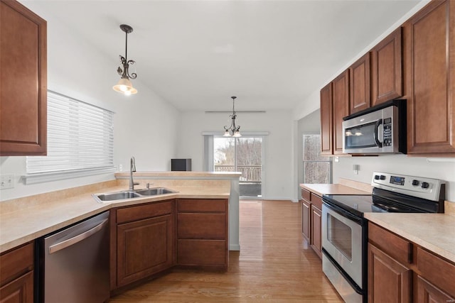 kitchen with light countertops, appliances with stainless steel finishes, hanging light fixtures, and a sink