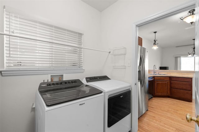 laundry area featuring light wood-type flooring, laundry area, independent washer and dryer, and a sink