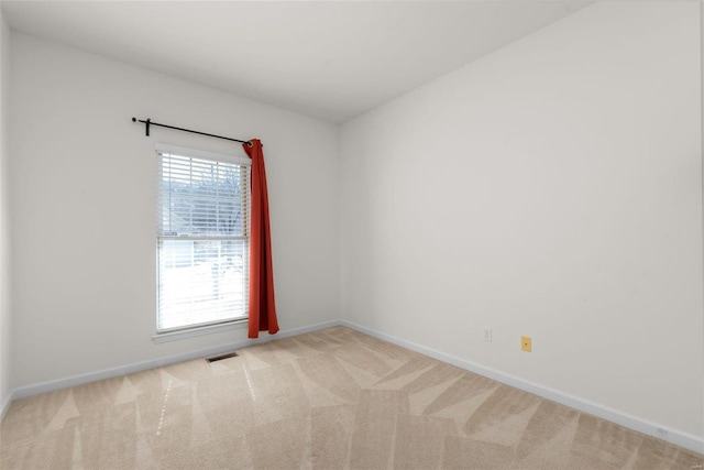 spare room featuring light carpet, a wealth of natural light, and baseboards