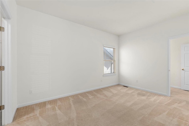 spare room with baseboards and light colored carpet