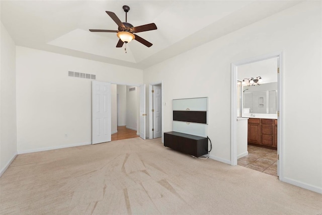 unfurnished bedroom featuring a raised ceiling, visible vents, light carpet, and baseboards