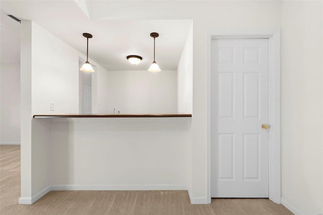 interior space with light carpet, a peninsula, baseboards, and pendant lighting