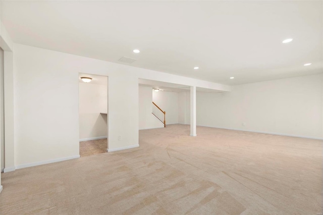 finished below grade area featuring stairway, baseboards, light colored carpet, and recessed lighting