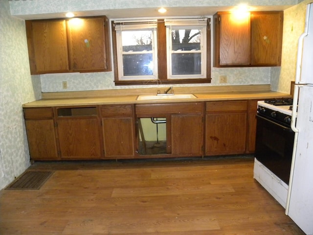 kitchen featuring white refrigerator, sink, range with gas cooktop, and light wood-type flooring