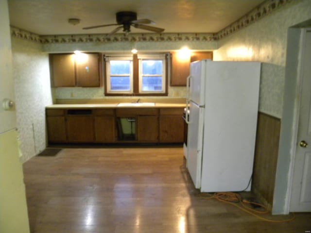 kitchen featuring sink, light wood-type flooring, ceiling fan, and white fridge