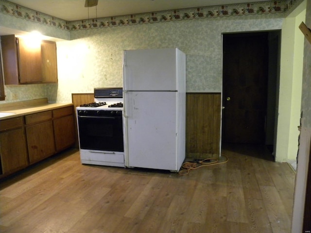 kitchen featuring gas range, light wood-type flooring, ceiling fan, and white fridge