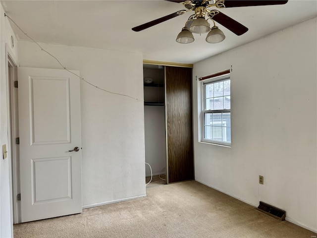 unfurnished bedroom featuring ceiling fan, light colored carpet, and a closet