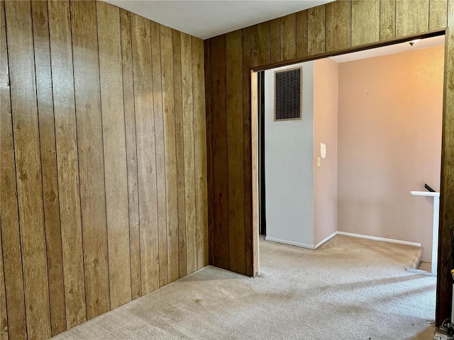 empty room featuring light colored carpet and wood walls