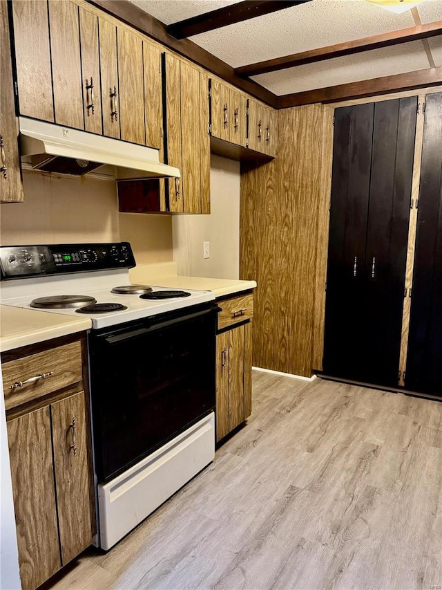 kitchen with beam ceiling, light hardwood / wood-style floors, a textured ceiling, and electric range