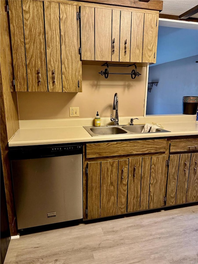 kitchen with stainless steel dishwasher, sink, and light wood-type flooring