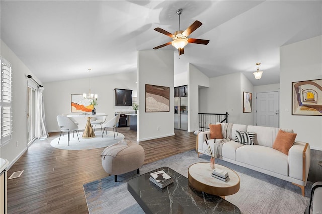 living room featuring ceiling fan with notable chandelier, dark hardwood / wood-style floors, and vaulted ceiling