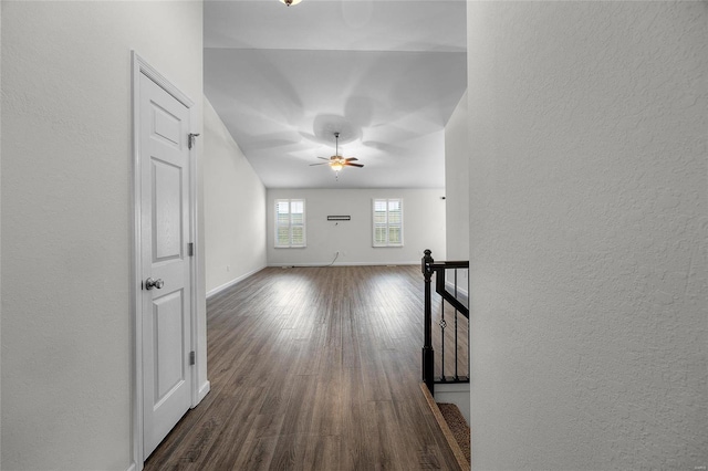 unfurnished living room featuring dark wood-type flooring and ceiling fan