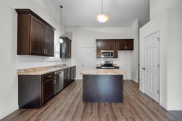 kitchen featuring a kitchen island, tasteful backsplash, sink, hanging light fixtures, and stainless steel appliances