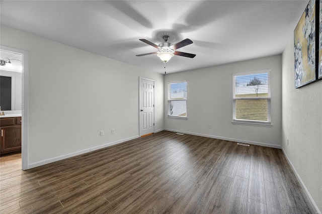 empty room with ceiling fan and dark hardwood / wood-style flooring