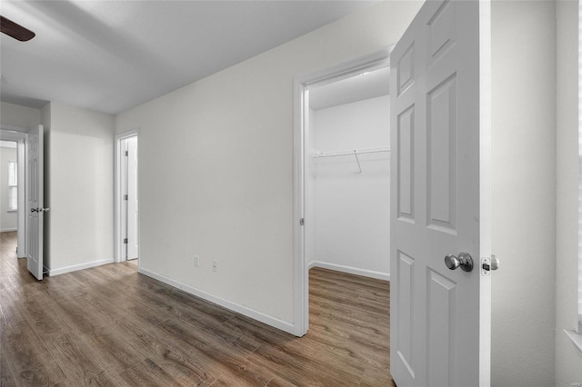 unfurnished bedroom with a spacious closet, dark wood-type flooring, and a closet